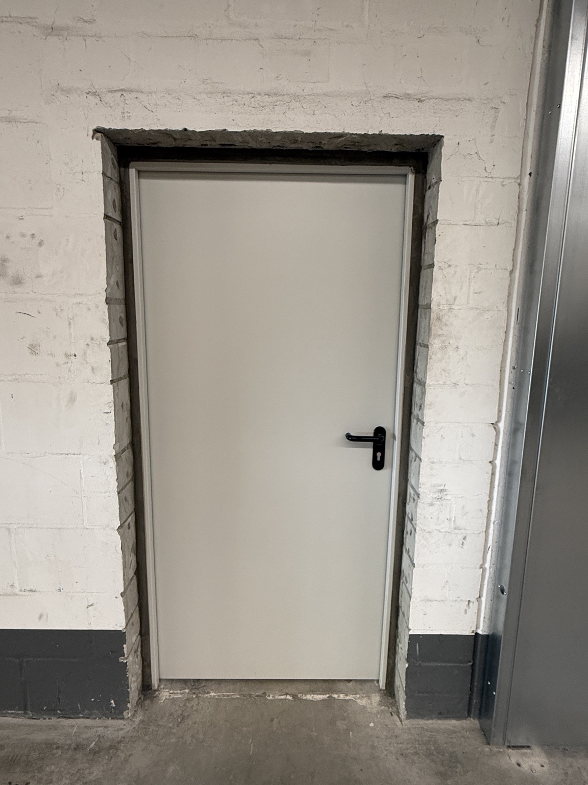 Separate Brandschutztür neben dem Schiebetor; die angrenzenden Wandflächen sind noch unverputzt.